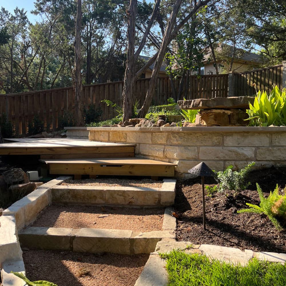 Stone steps lead to a landscaped garden with greenery and a water feature.