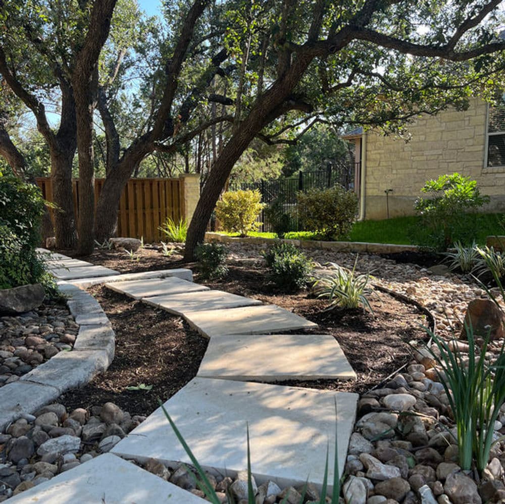 landscaped garden path with stone steps, surrounded by trees and ornamental plants