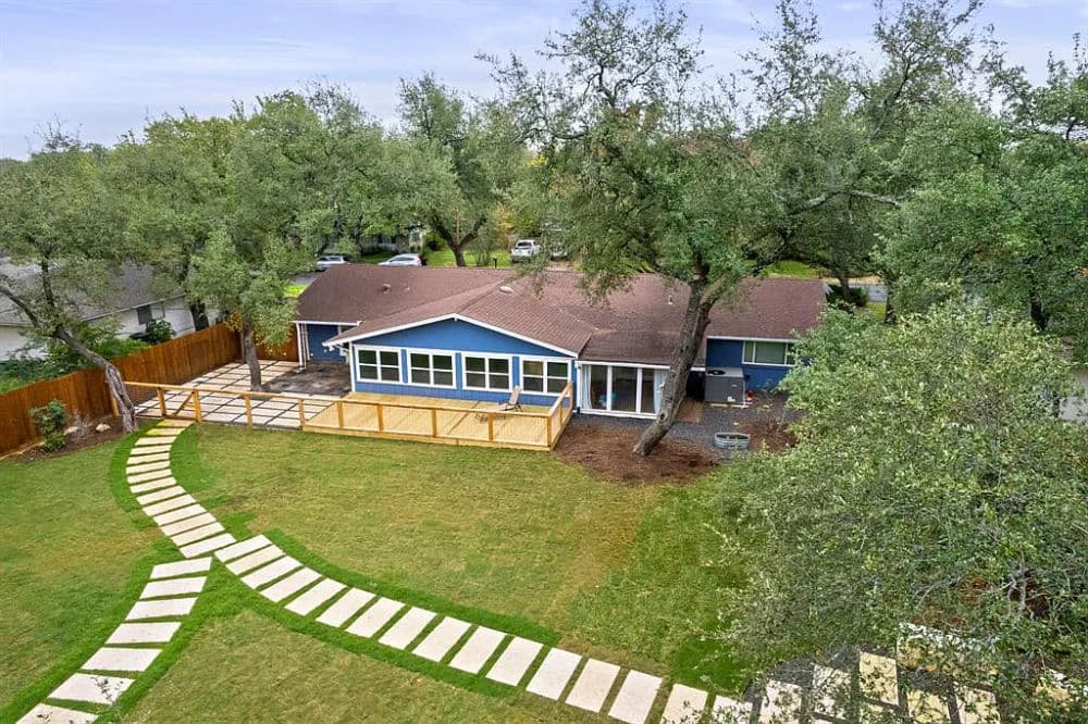 Spacious blue single-story house with a landscaped yard and stone pathway.
