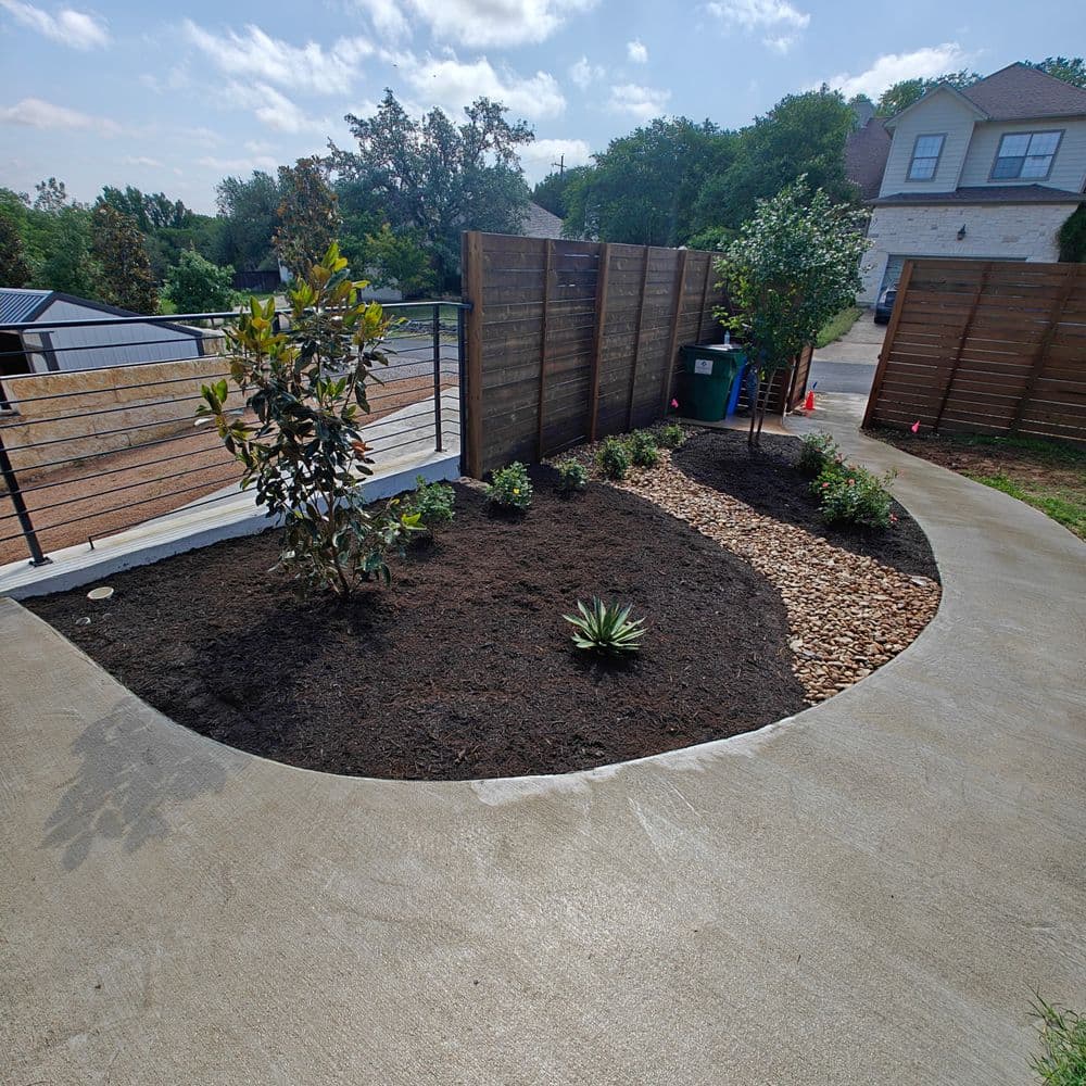 Modern landscaped garden with curved paths, wooden fencing, and various plants.